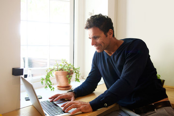 Handsome middle aged man with laptop at home