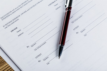 Pen and contract papers on wooden desk