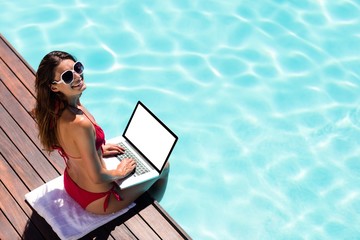 Woman using her laptop on the pool edge