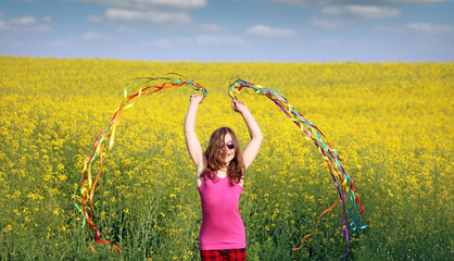 happy little girl waving with colorful ribbons on field