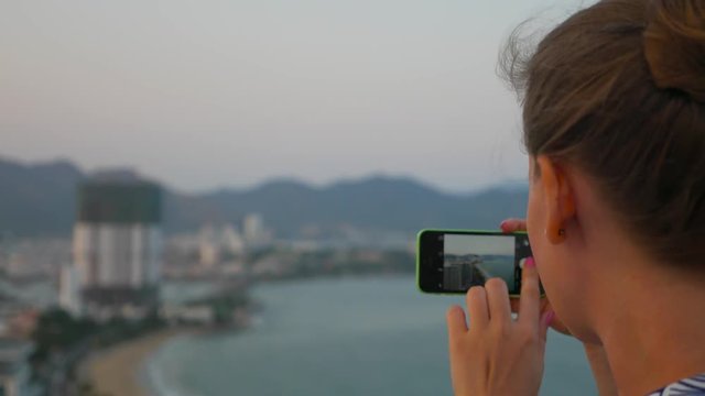 Close up of caucasian woman taking photo of cityscape be hir smartphone. Nha Trang, Vietnam.