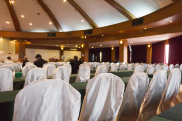 Blurred background of empty chairs with people in convention or