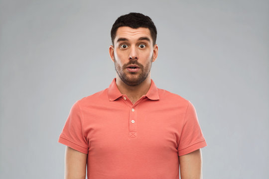 surprised man in polo t-shirt over gray background