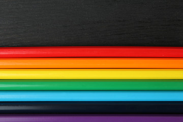a lot of colored pencils lying closeup on wooden background