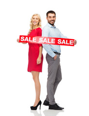 couple with red sale sign standing to back 