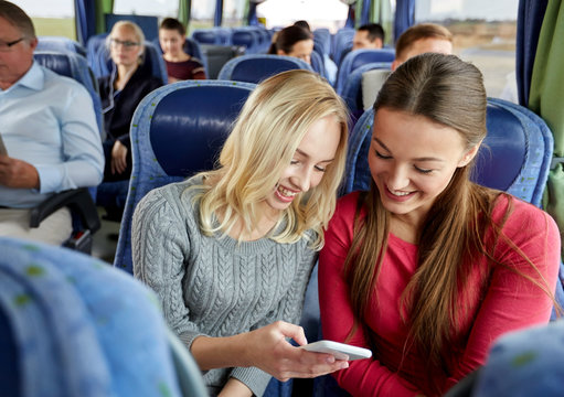 happy young women in travel bus with smartphone