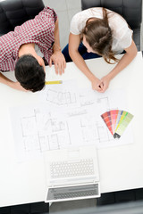 young couple planning decoration project of their new home with blueprint