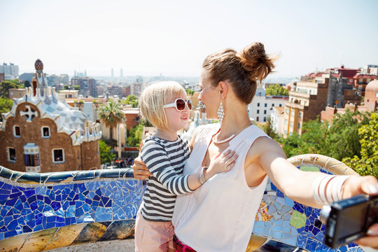 Happy mother and baby taking selfie with camera at Park Guell