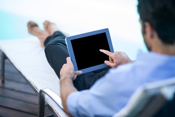 Man using digital tablet near pool