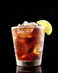 Cold cola with ice in a glass on a black background
