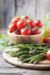 Raw asparagus with tomato on the wooden table