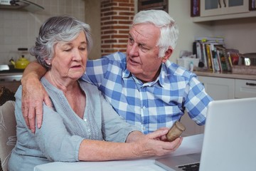 Senior man consoling wife holding pills container