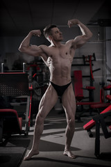 Fototapeta na wymiar Handsome bodybuilder posing in gym. Perfect muscular male body