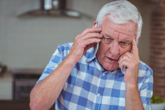 Worried Senior Man Talking On Mobile Phone