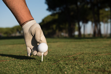 close up of golf players hand placing ball on tee