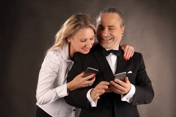 Eine Frau und ein Mann blicken lachend auf ihre Mobiltelefonen