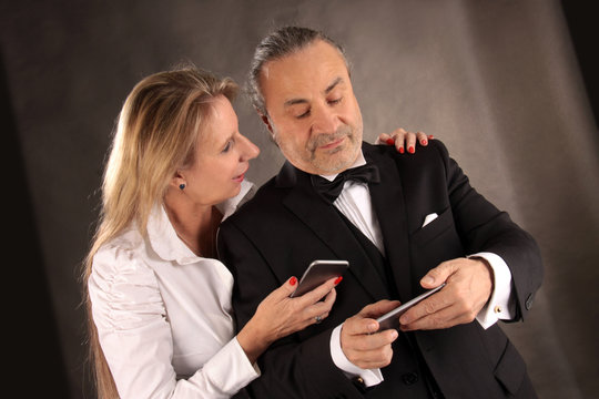 Eine Frau und ein Mann mit Smartphones und festlich gekleidet