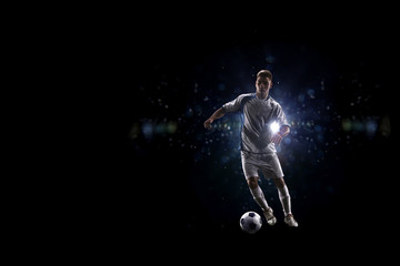 Fototapeta na wymiar Soccer player in action over black background
