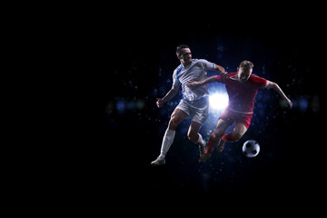 Fototapeta premium Soccer players in the air over black background
