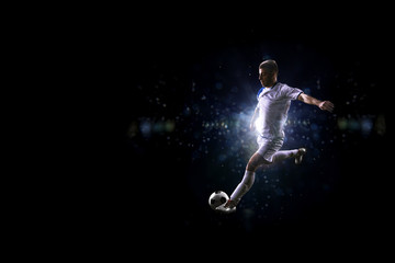Naklejka na ściany i meble Soccer player in action over black background