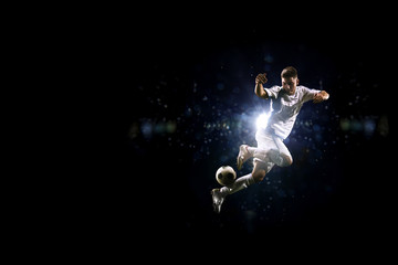 Fototapeta na wymiar Soccer player in action over black background