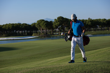 Obraz premium golf player walking and carrying bag