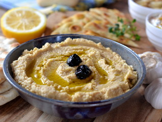 Hummus, Houmous, on wooden board with pita, lemon and garlic.