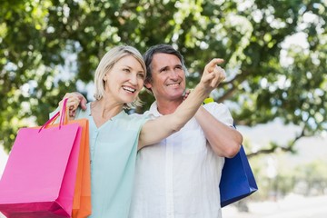 Naklejka premium Woman pointing to happy man with shopping bags