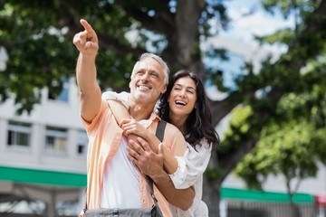 Man pointing while woman hugging him from behind