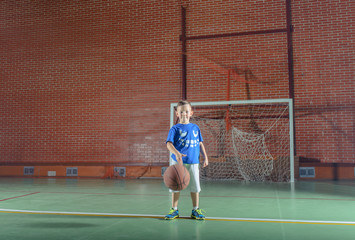 Obraz premium Sporty little boy playing basketball