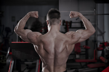 Fototapeta na wymiar Handsome bodybuilder posing in gym. Perfect muscular male body