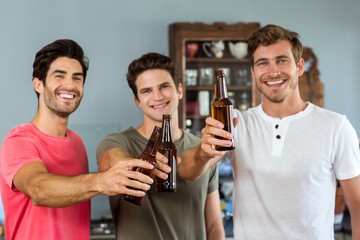 Portrait of male friends toasting beer bottles