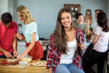 Young woman holding beer bottle at home
