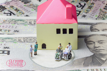 車椅子に座る老夫婦 Old couple sitting in a wheelchair with house and bill 