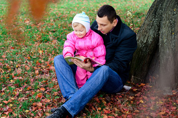 Father and daughter sitting under a tree Fall