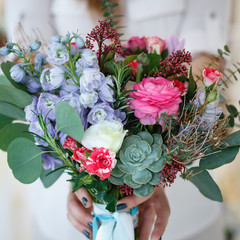 young woman holds a bouquet she made