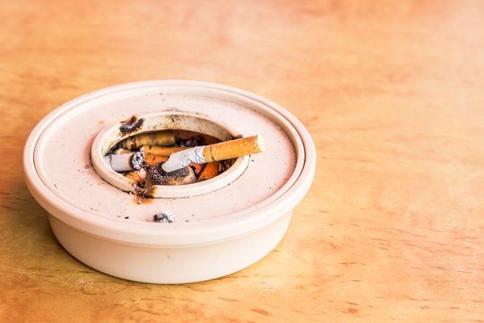 Cigarette butts in ashtray placed on table flushed left
