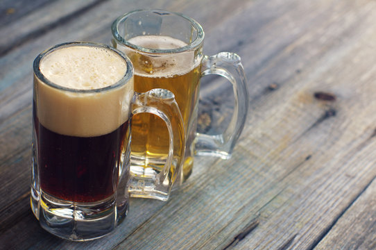Two glasses of beer. Light and dark beer in glasses on a wooden board.