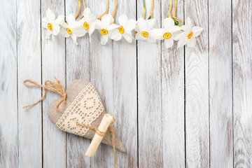 Narcissus flower, decorative heart on a light wooden background. Selective focus. Space for text.