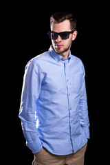 young handsome man in sunglasses posing isolated on black