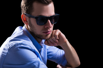 young sad man in sunglasses thinking about something over black