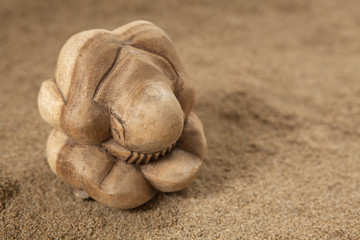 Fototapeta na wymiar yogi bouddha en bois sur sable