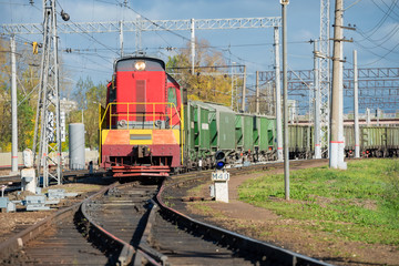 Fototapeta na wymiar Red locomotive and Green freight cars on the rails