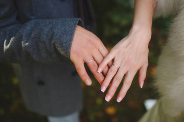 Hands of newlyweds with wedding rings over bouquet of red roses