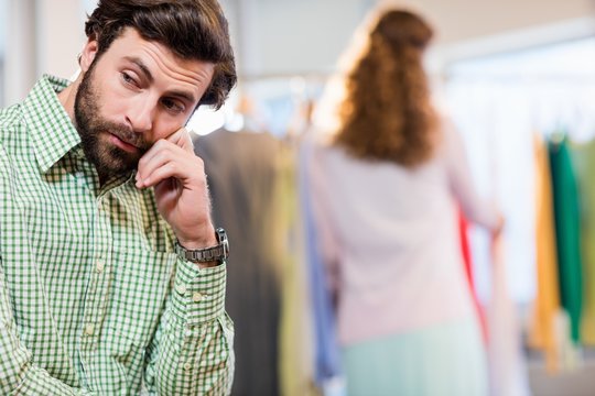 Bored Man Waiting His Wife While Woman By Clothes Rack