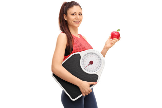 Woman holding an apple and a weight scale