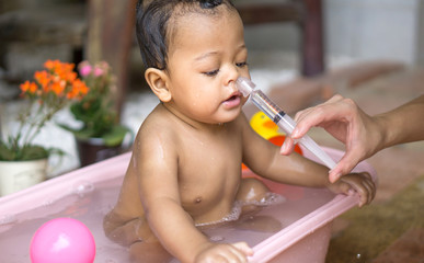 Asian baby saline nasal wash - obrazy, fototapety, plakaty
