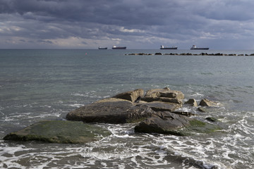 Stones on the shore and ships at sea. Limassol's seafront promenade. Cyprus.