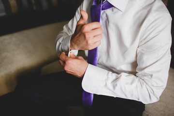 Businessman going to work. Man buttons cuff links. Purple tie