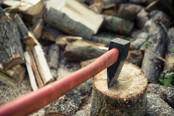 Axe stuck in a stump on  background of chopped firewood
